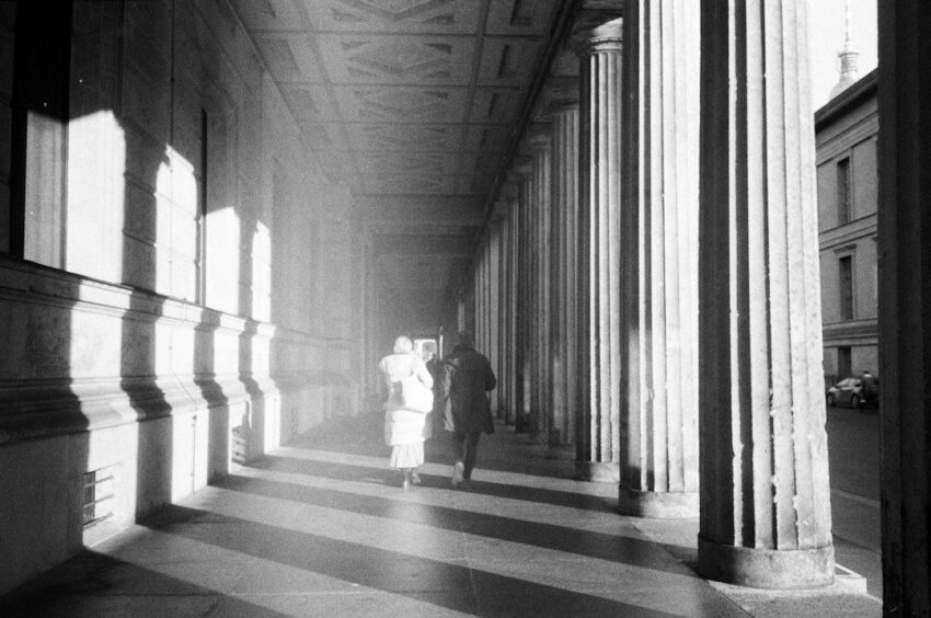Historische Säulenhalle mit zwei Menschen im starken Morgenlicht
