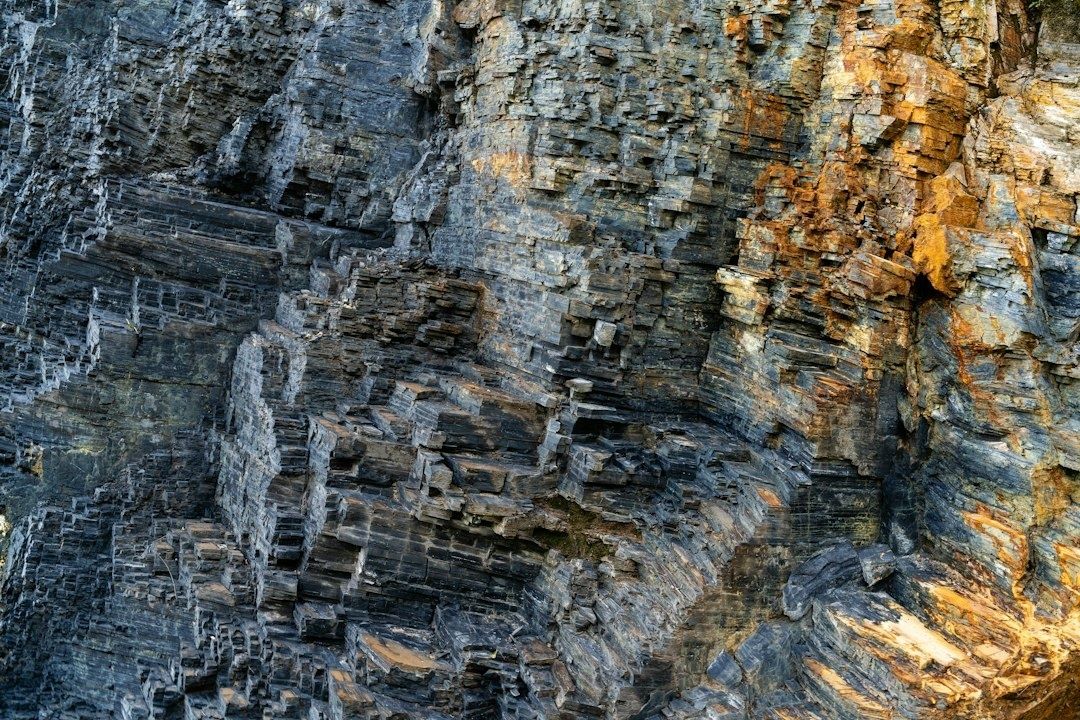 Nahaufnahme geschichteter, dunkelgrauer und rostbrauner Felsstrukturen